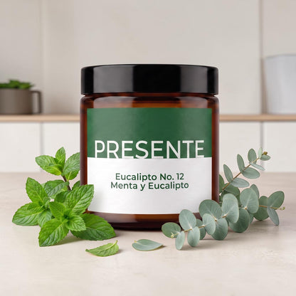 Vela aromática PRESENTE Taller Artesanal Eucalipto No. 12 en frasco de vidrio ámbar con hojas de eucalipto y menta fresca.