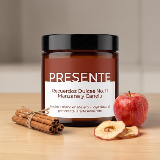 Vela aromática PRESENTE Taller Artesanal de manzana y canela en frasco de vidrio ámbar con manzana fresca y ramas.